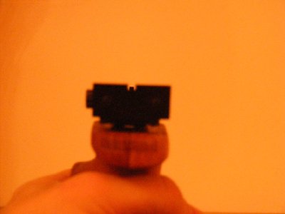 Otprilike bi ovako trebali izgledati ciljnici pri ciljanju. Prednji u fokusu i po sredini utora zadnjeg ciljnika. Trebao bi biti malo više da vrh bude poravnat s vrhom zadnjeg ciljnika. Zadnji ciljnik malo mutan jer fokus mora biti na prednjem ciljniku. Ovdje je bilo problema jer sam pištolj držao lijevom rukom dok sam desnom pokušavao okinuti fotku. Obzirom koliko je sve nespretno, čudim se kako sam uspio dobiti toliko dobru poziciju. Inače kad ciljam prednji ciljnik mi je nešto udaljeniji od oka pa izgleda deblje nego što je na slici.